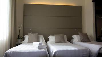 Habitación de hotel con dos camas, un cabecero grande sujeto a la pared y una planta en maceta.