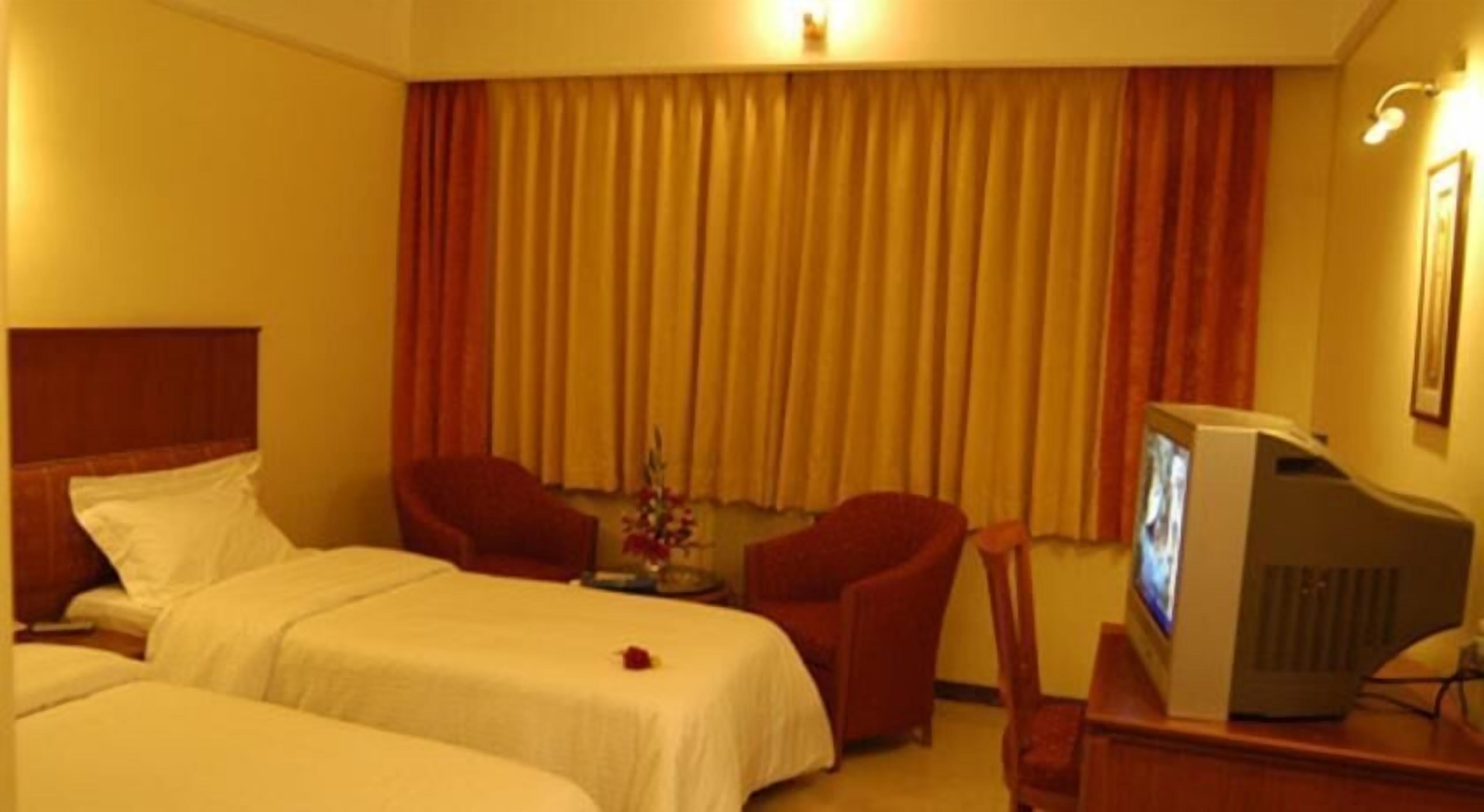 A hotel room with two beds, a TV, a desk, and a chair.