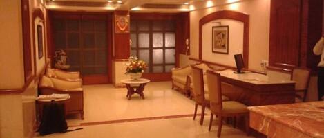 A hotel lobby with a reception desk, seating area, and a large window.