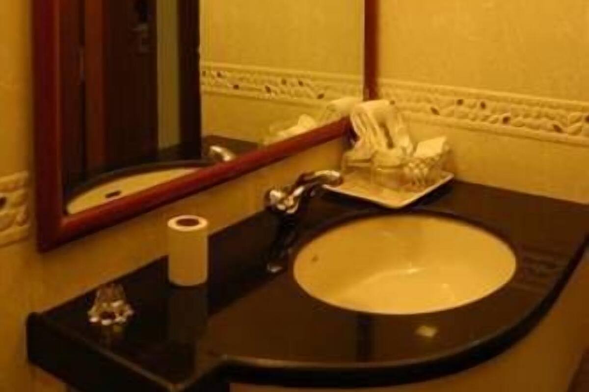 A bathroom with a large mirror, a sink, and a toilet.