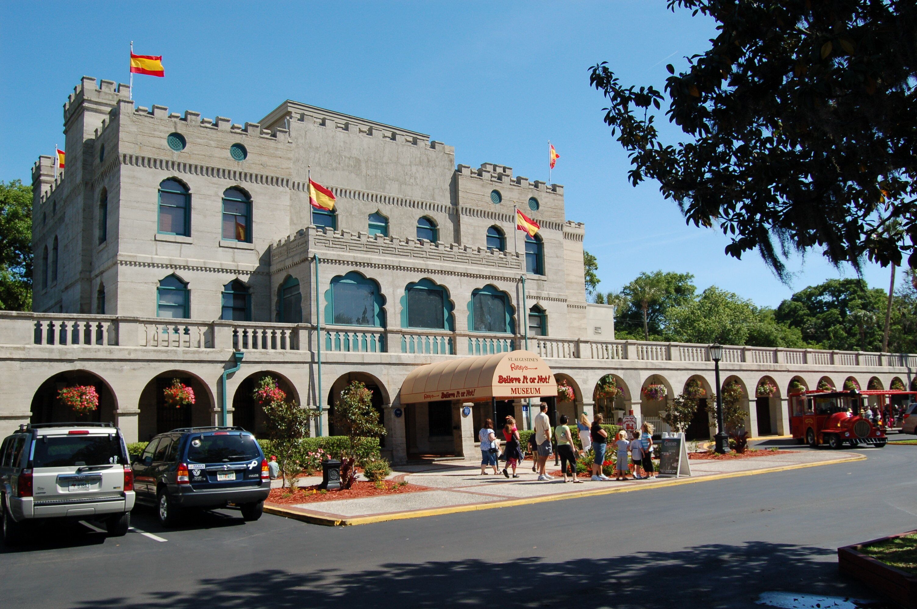 A historic building with a museum entrance, arched windows, and flags.