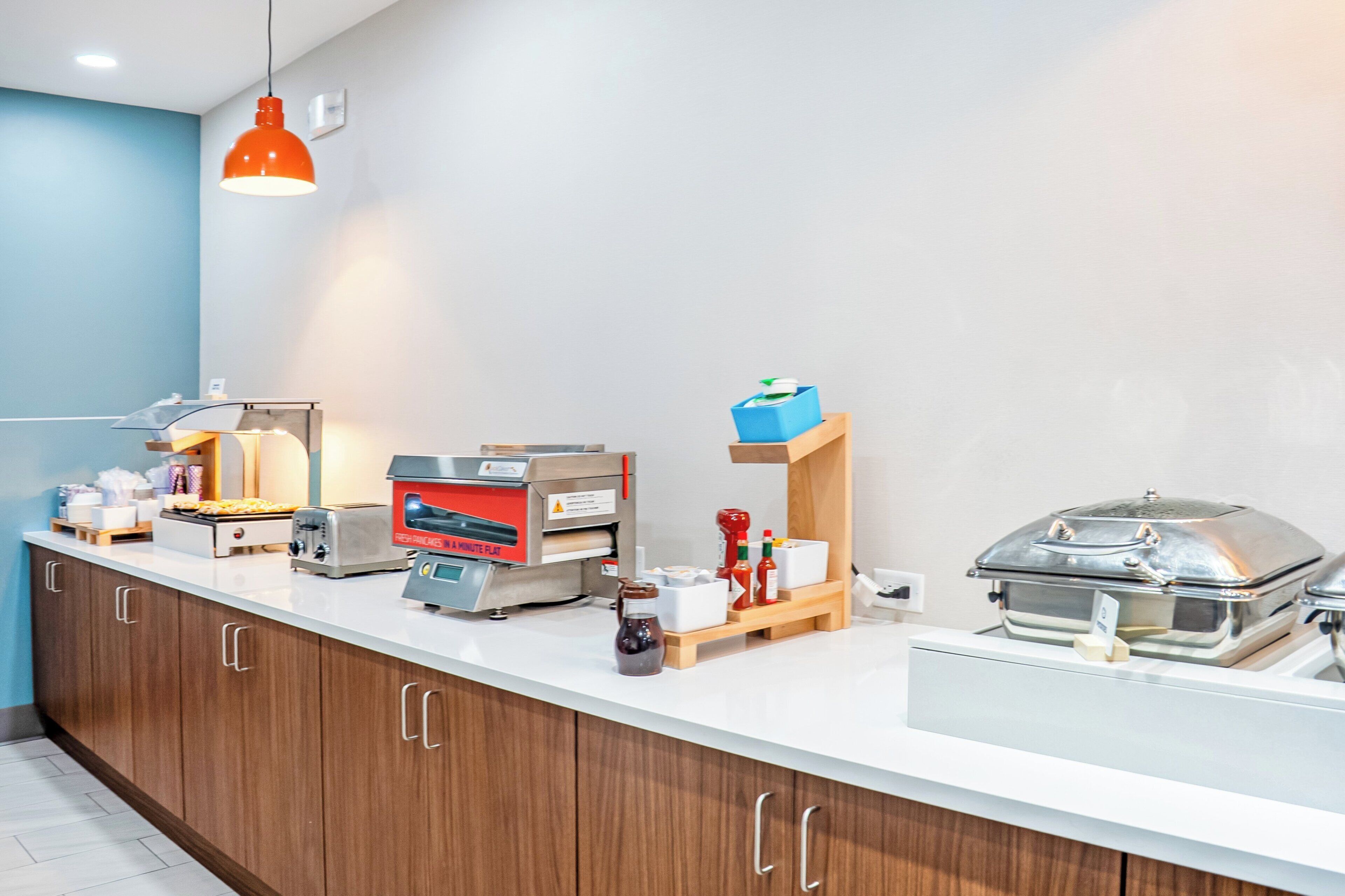Een ontbijtbalk met een broodrooster, een koffieapparaat, toevoegingen en een warmhoudapparaat voor eten.