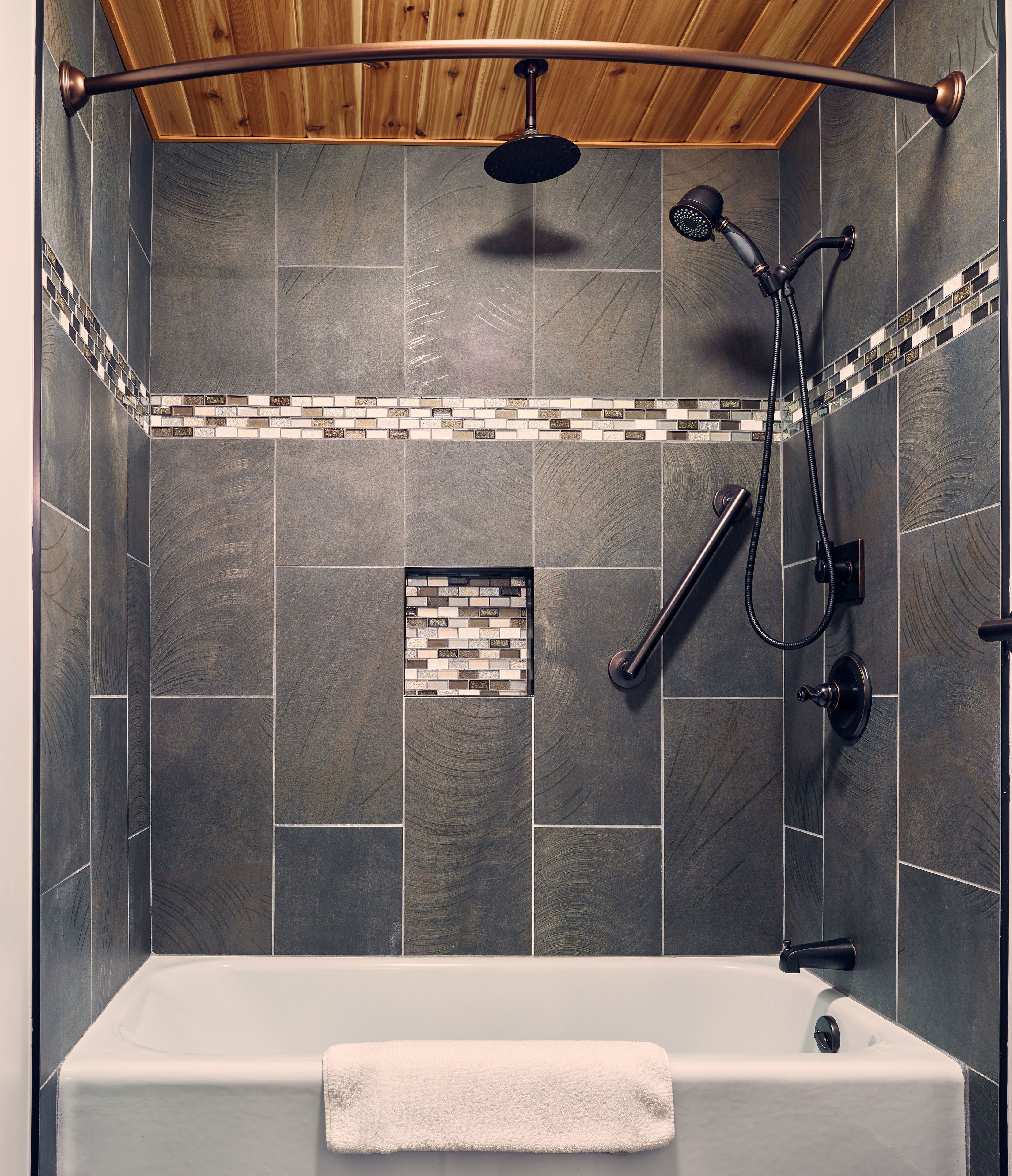 A modern shower area with a bathtub, a rain showerhead, a handheld showerhead, and a handheld shower hose.