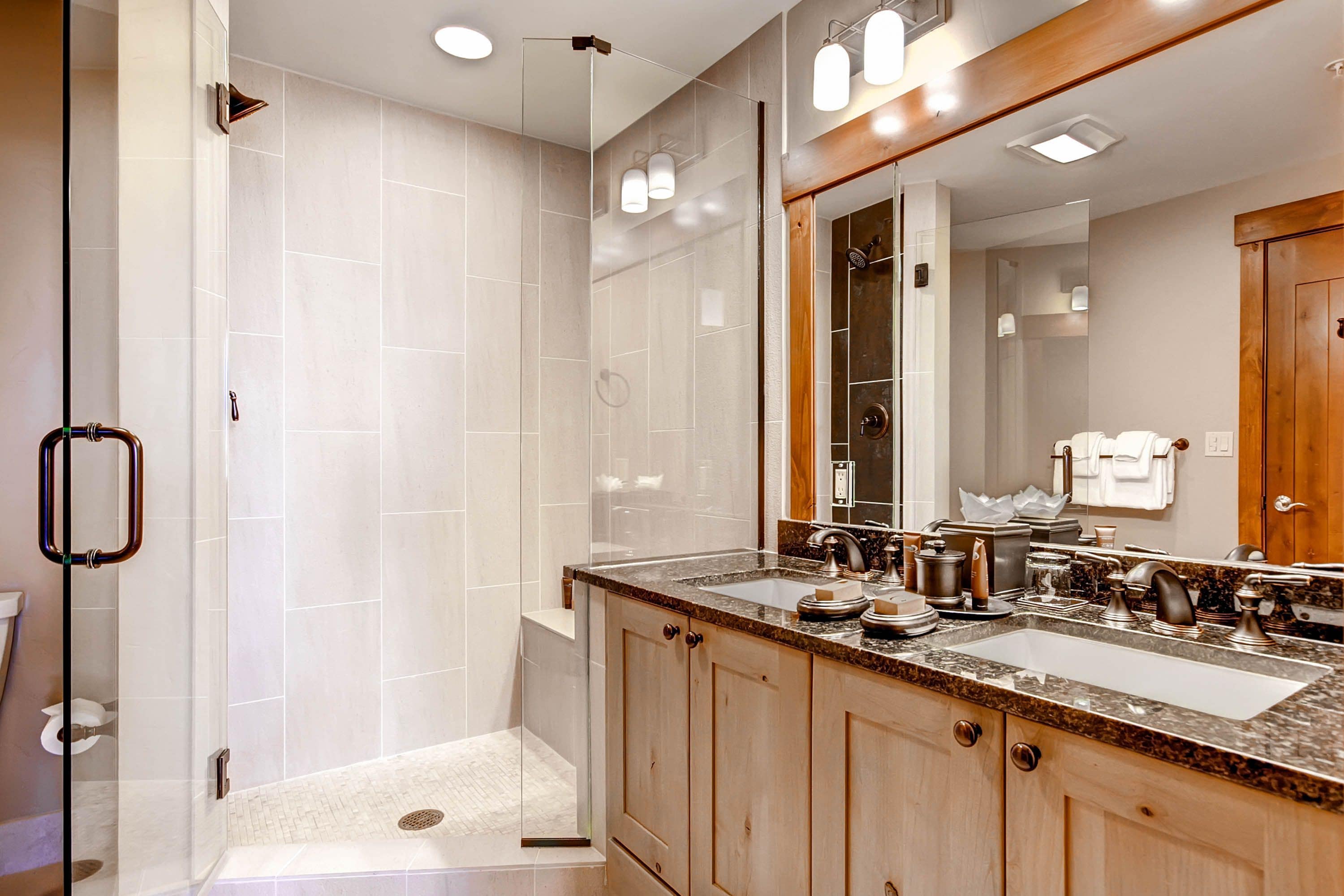 A modern bathroom with a walk-in shower, a large vanity with a double sink, and a mirror with a wooden frame.