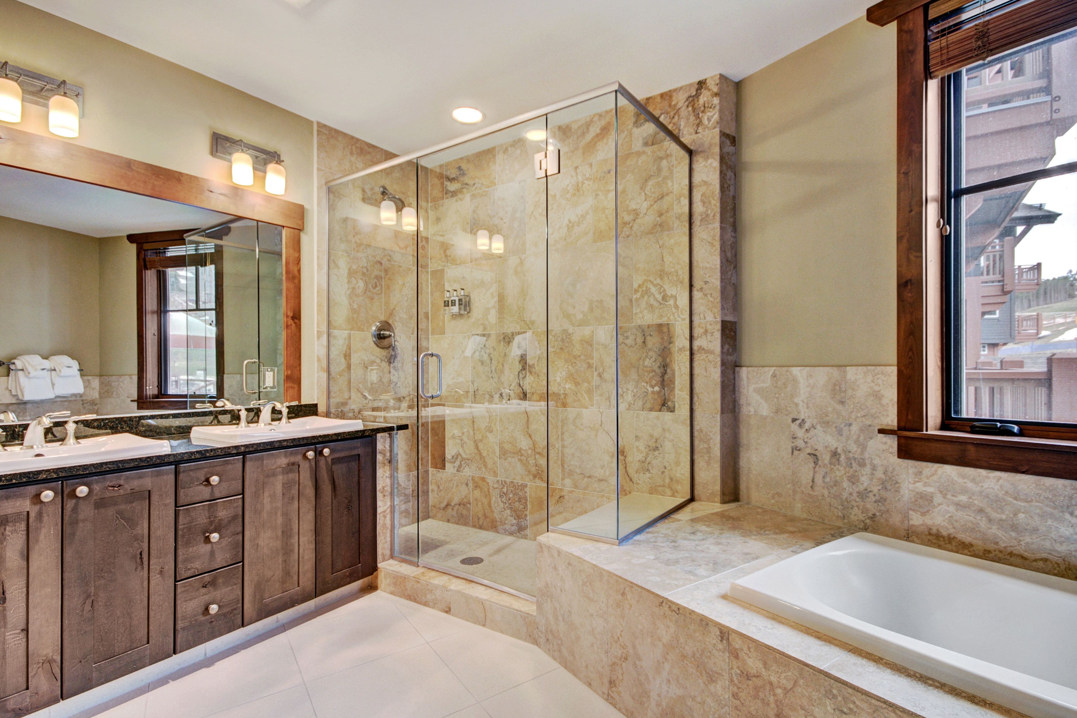 A modern bathroom with a glass-enclosed shower, a double sink vanity, and a large bathtub.