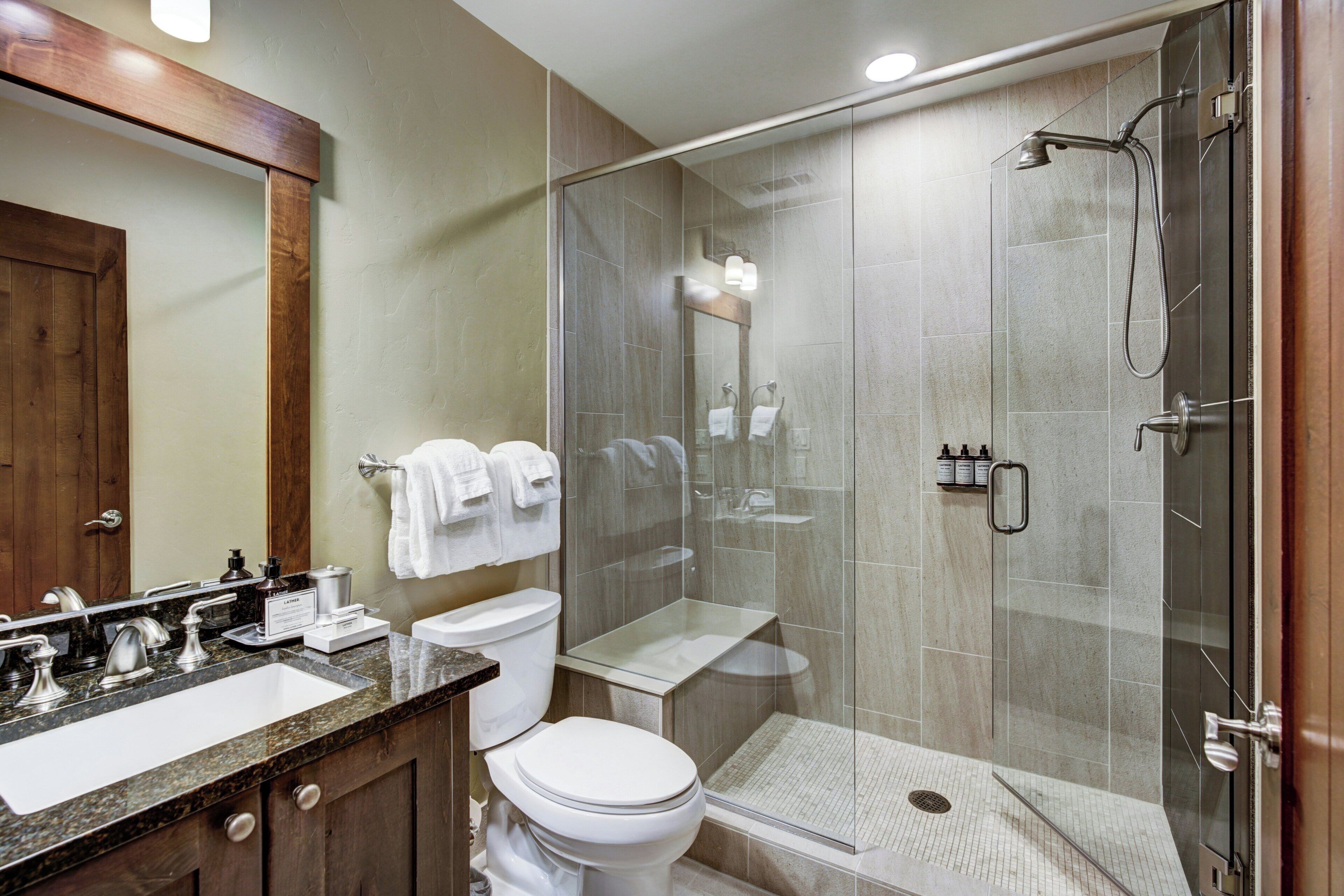 A modern bathroom with a glass-enclosed shower, a vanity with a sink, and a toilet.