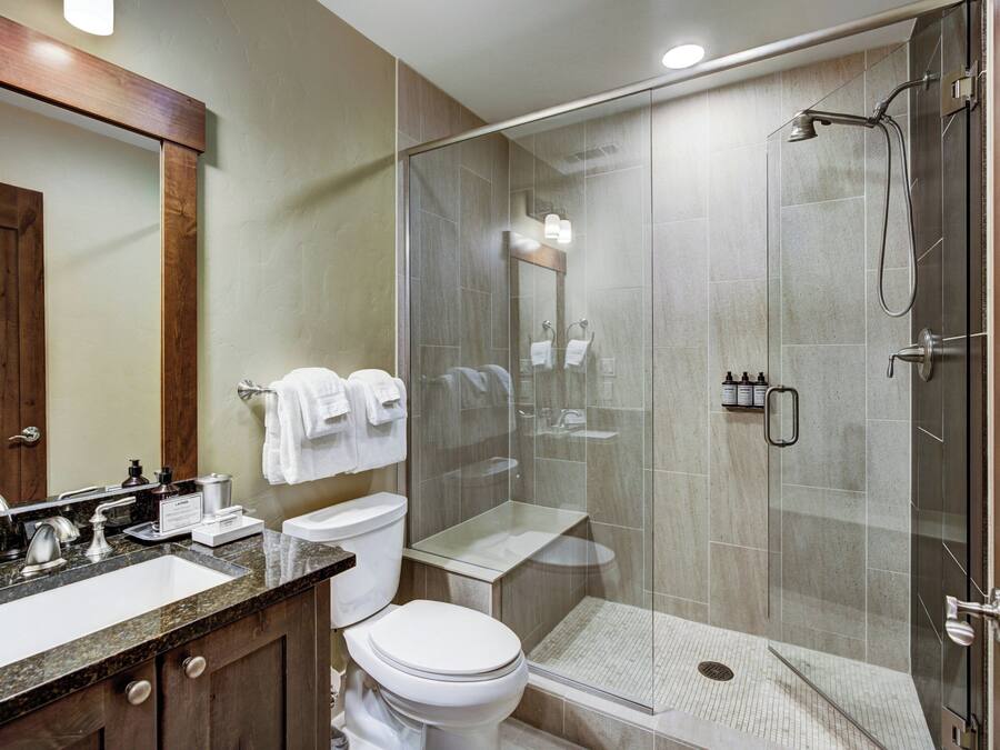 Een moderne badkamer met een douchecabine van glas, een wastafelmeubel met een wastafel en een toilet.