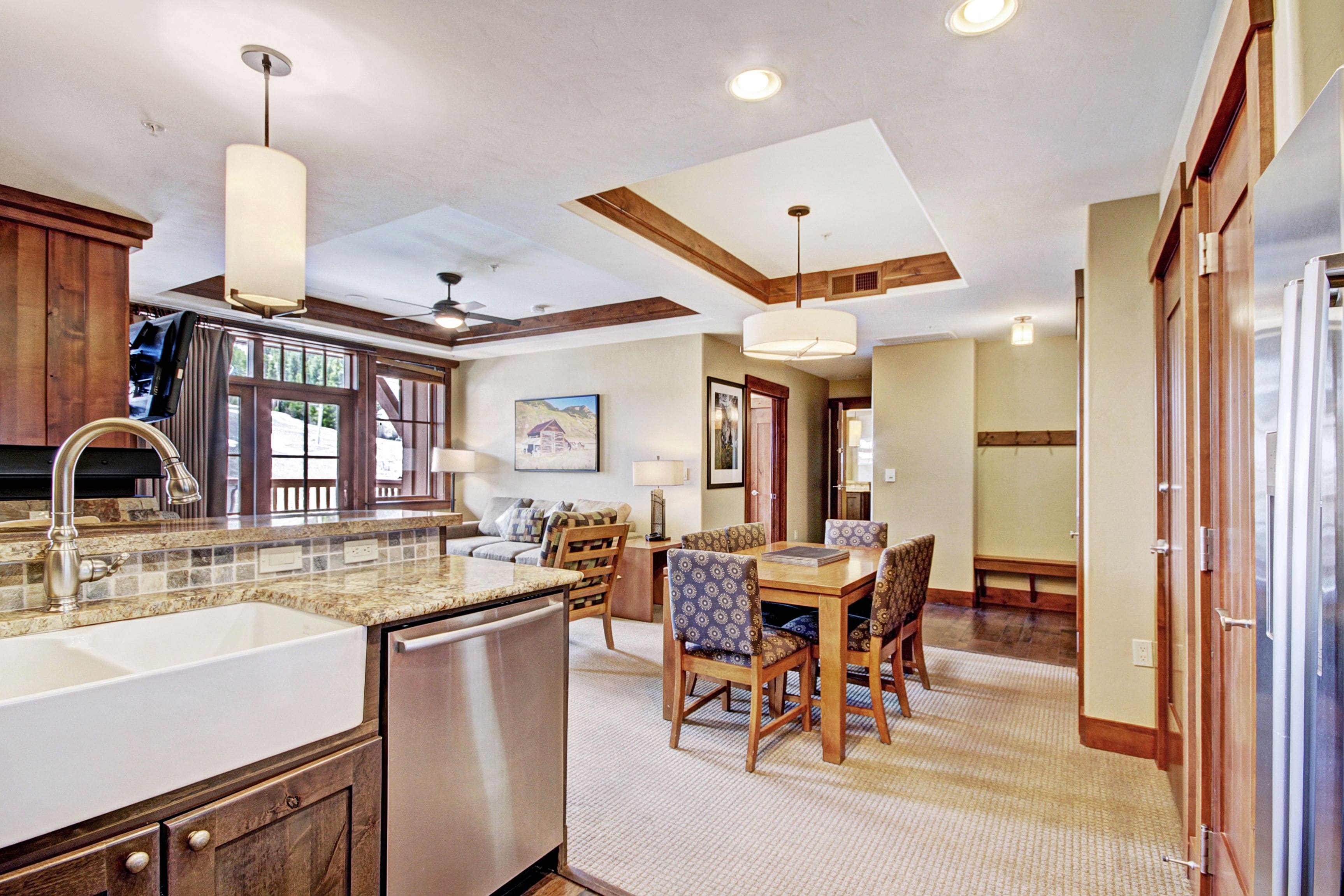 A kitchen with a large island, wooden cabinets, and a dining area with a table and chairs.