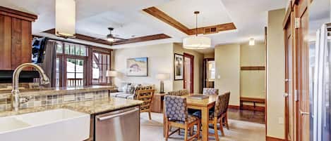 A kitchen with a large island, wooden cabinets, and a dining area with a table and chairs.