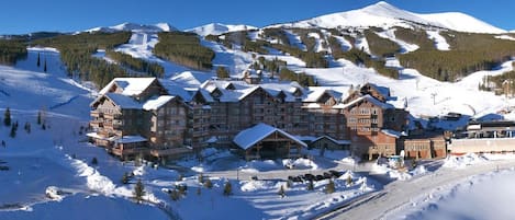 Un gran edificio tipo lodge con varios pisos y una pista de esquí al fondo.