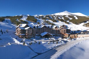 A large lodge with multiple floors and a ski slope in the background.