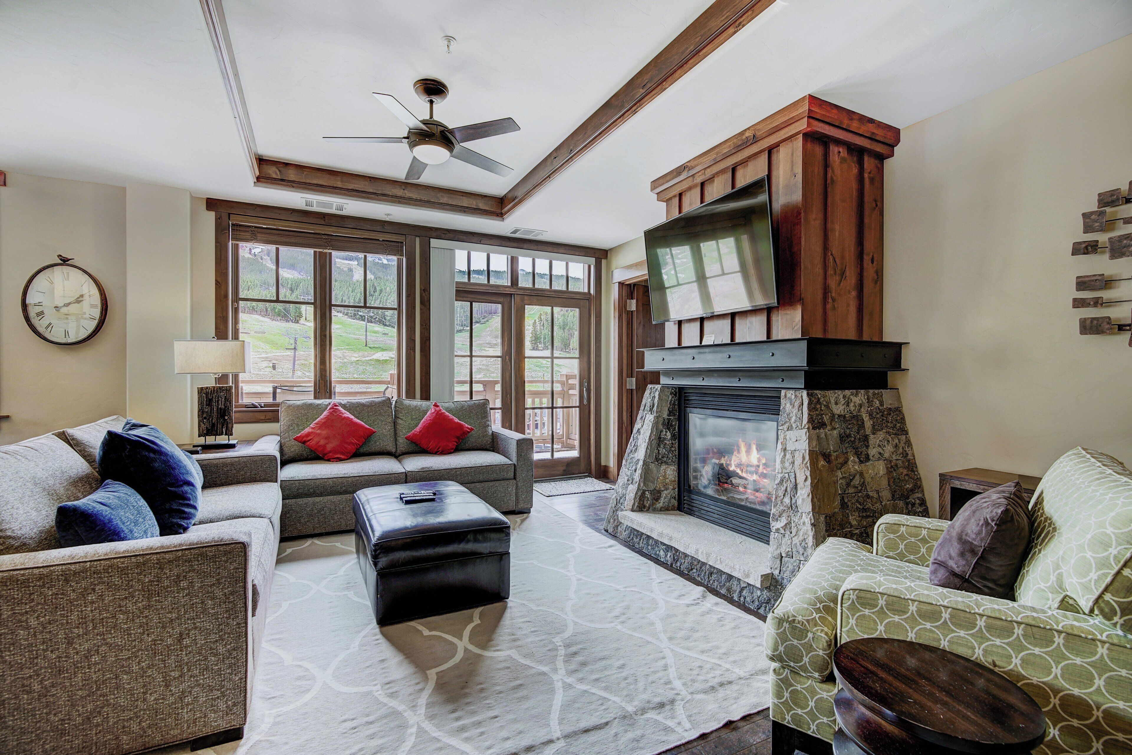 A living room with a fireplace, two sofas, a coffee table, and a ceiling fan.
