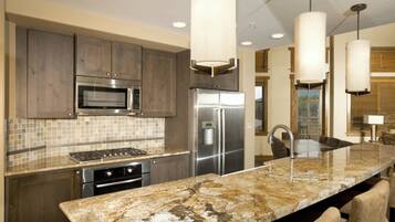 A modern kitchen with granite countertops, stainless steel appliances, and pendant lighting.