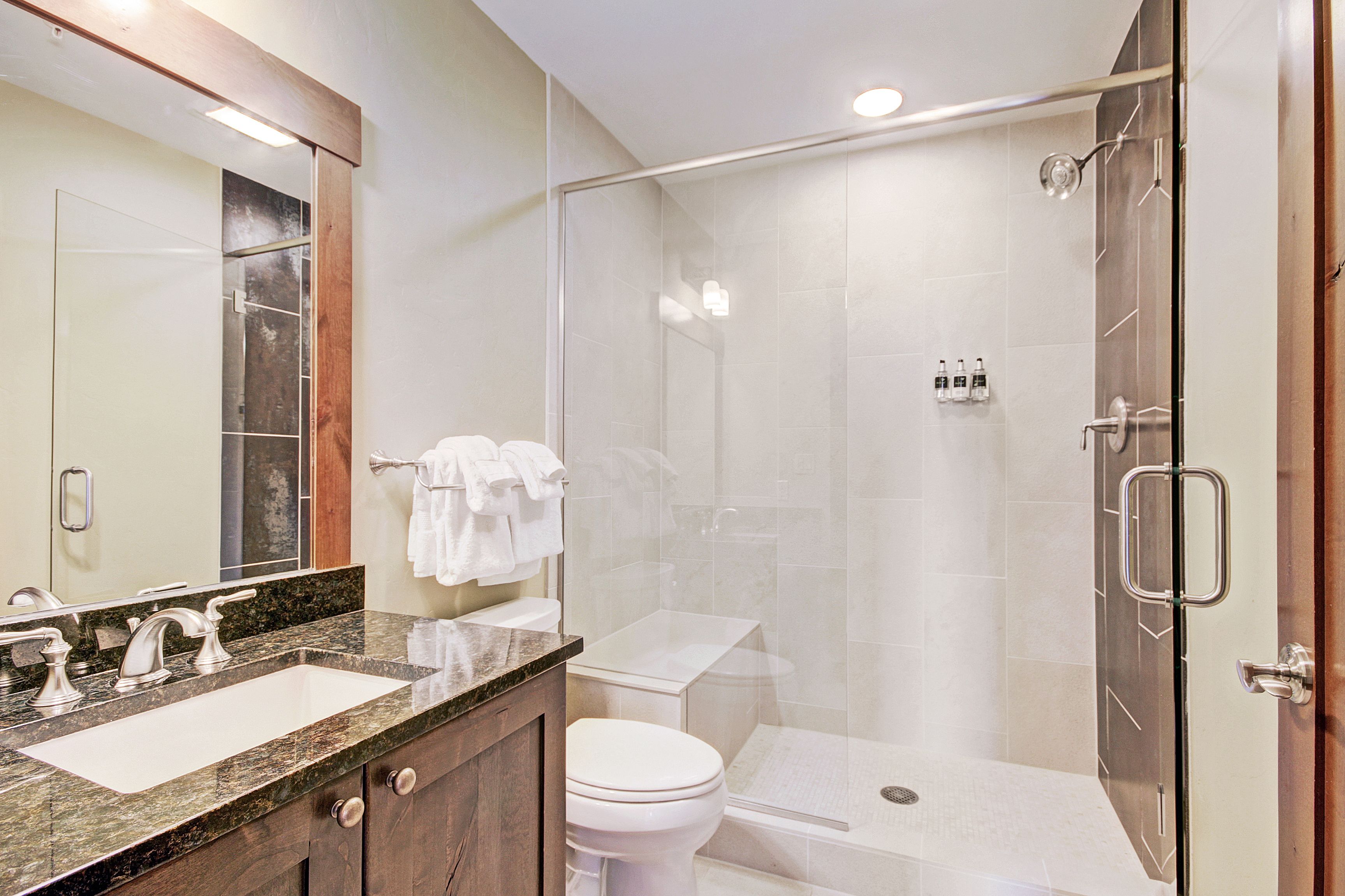 Une salle de bain moderne avec une douche à parois de verre, un meuble-lavabo à deux vasques et des toilettes.