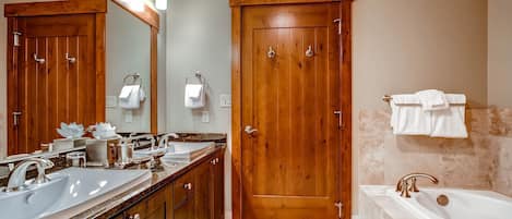 Une salle de bain avec des portes en bois, un lavabo, une baignoire et un grand miroir.