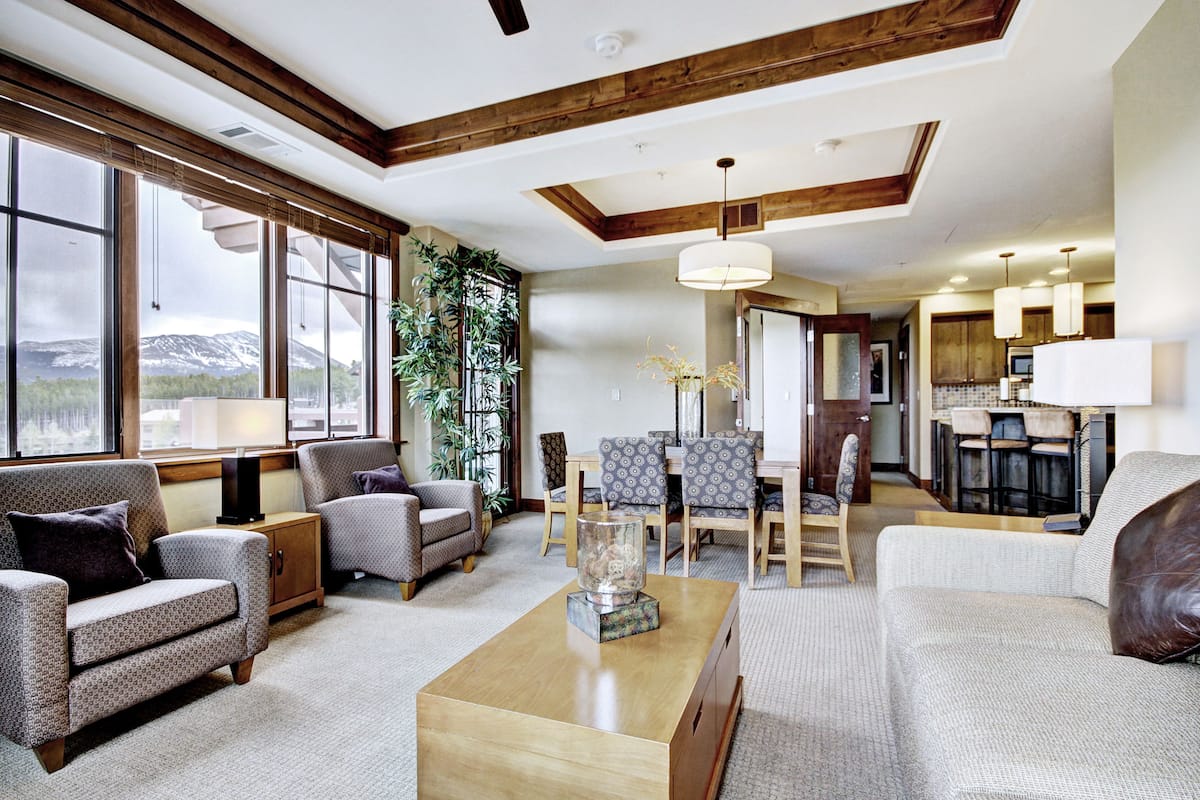 A spacious living room with a large window, a dining area, and a kitchen.