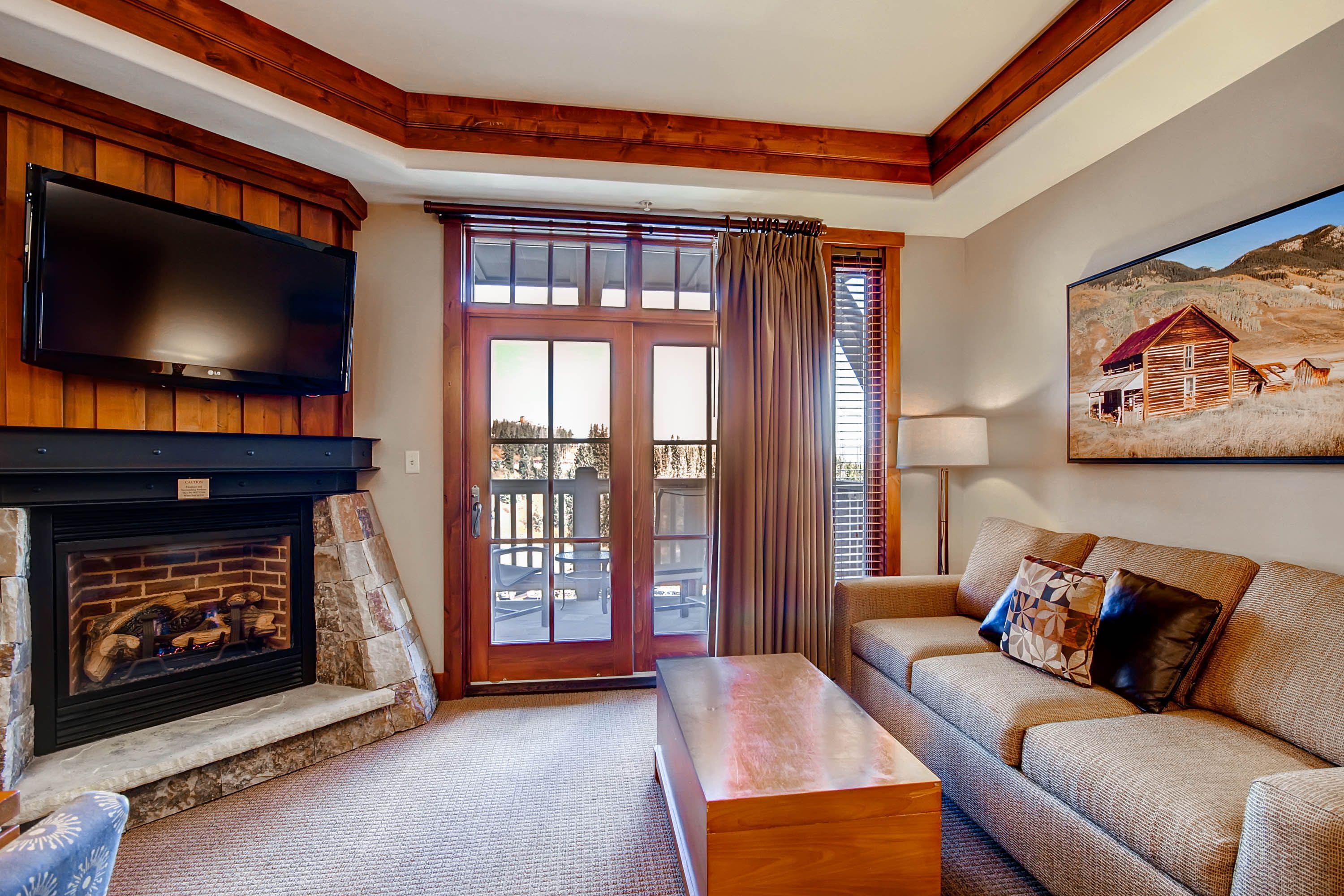 A living room with a fireplace, a television, a sofa, and a painting of a rural scene.