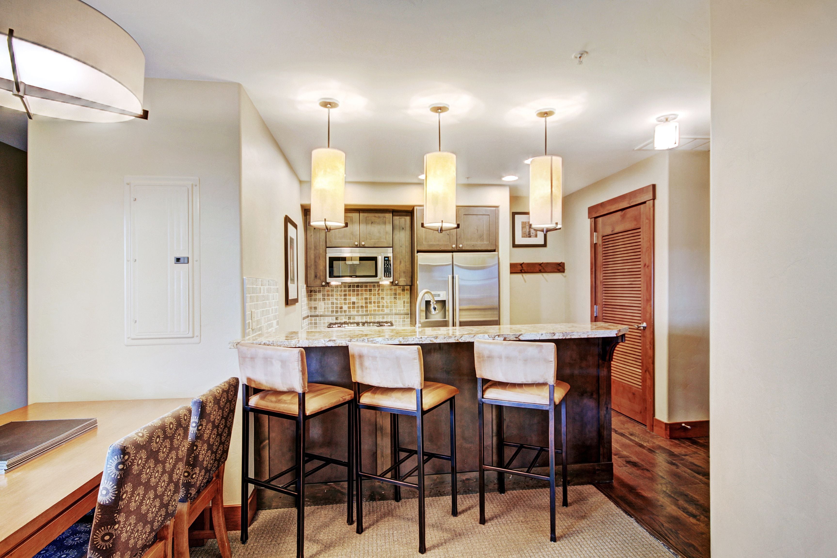 A modern kitchen with a central island, bar stools, and pendant lighting.