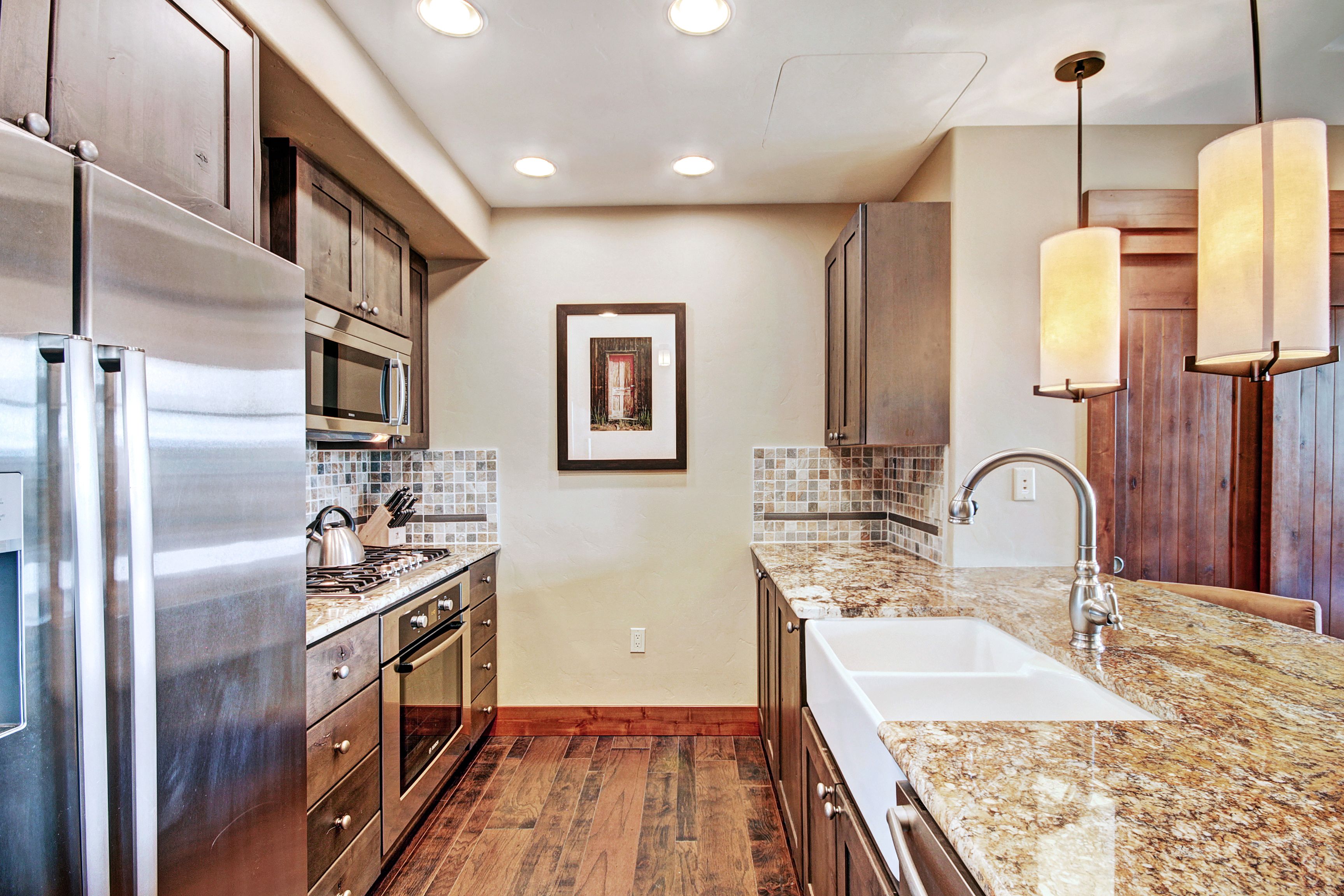 A modern kitchen with stainless steel appliances, a granite countertop, and wooden cabinets.