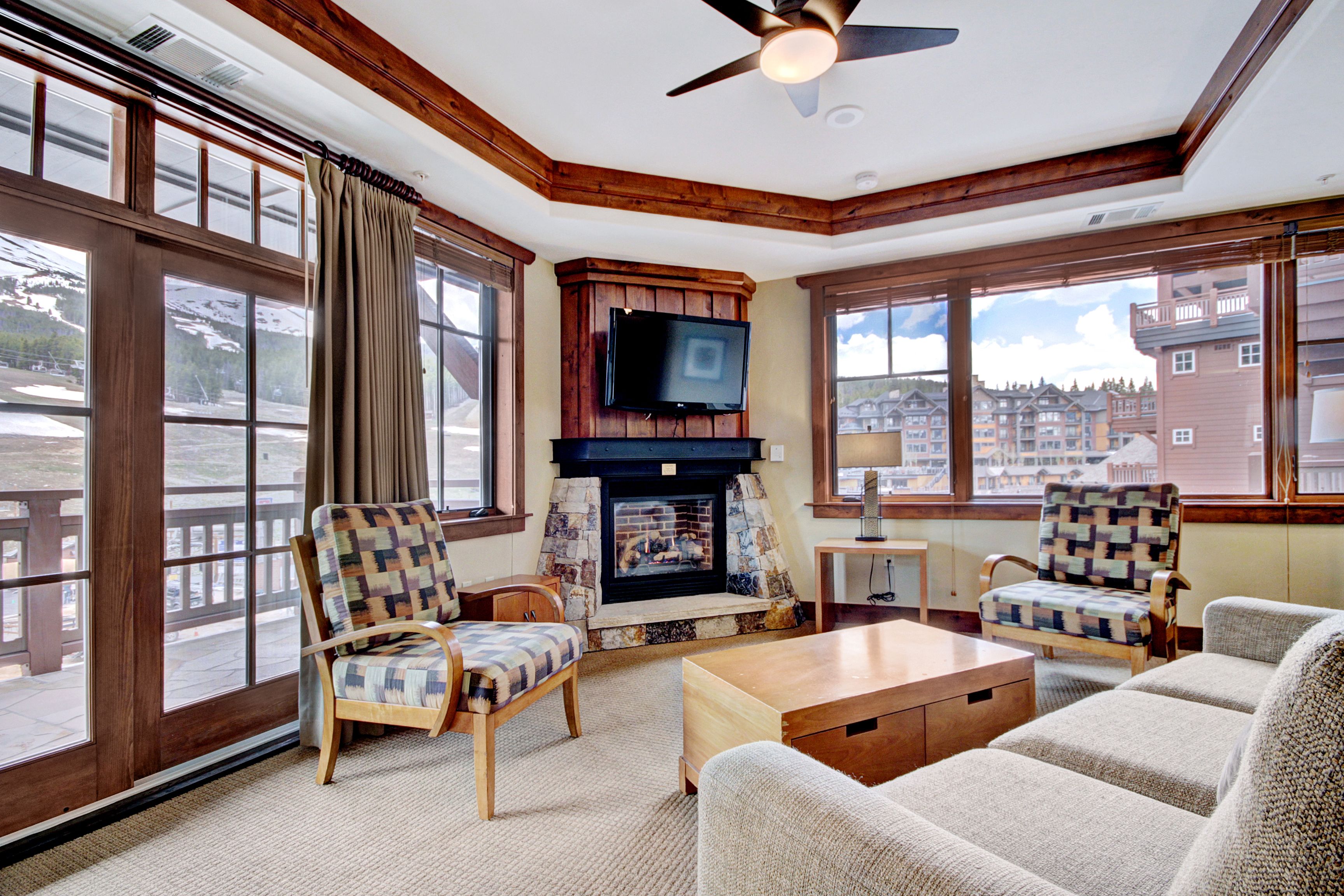 A cozy living room with a fireplace, large windows, and a television.