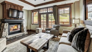 Una sala de estar con chimenea de piedra, un televisor de pantalla plana y un ventanal con vistas al paisaje.