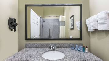 A bathroom with a granite sink, a large mirror, a towel rack, and a shower curtain.