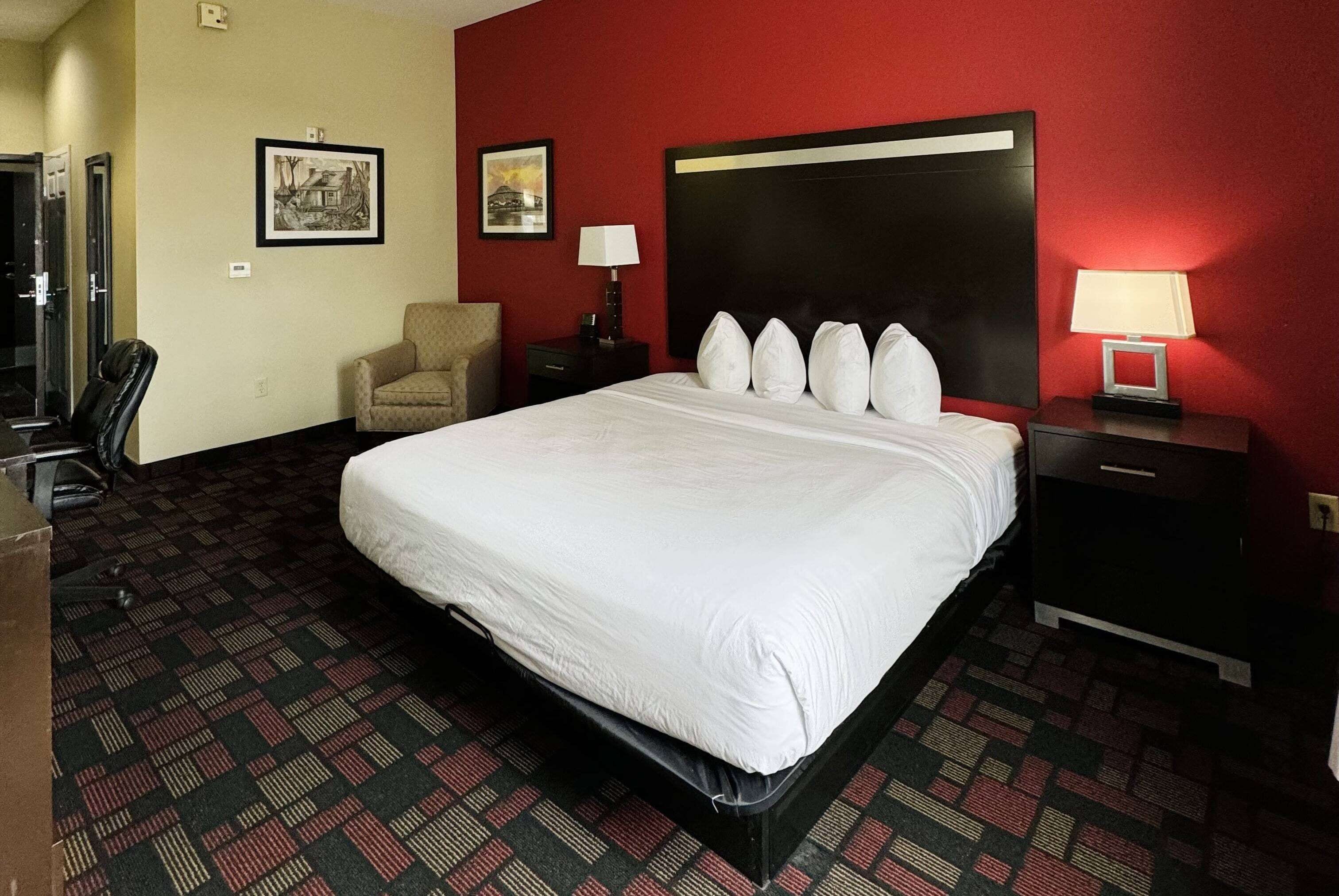 Una habitación de hotel con una cama grande, una silla, un escritorio y una mesita de noche.