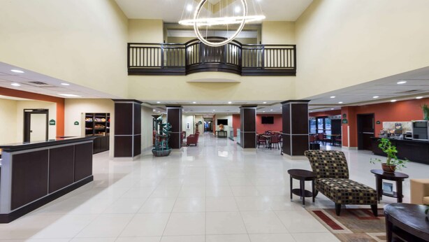 A spacious lobby with a reception desk, seating area, and a balcony. - Wingate by Wyndham Lake Charles Casino Area (Lake Charles)
