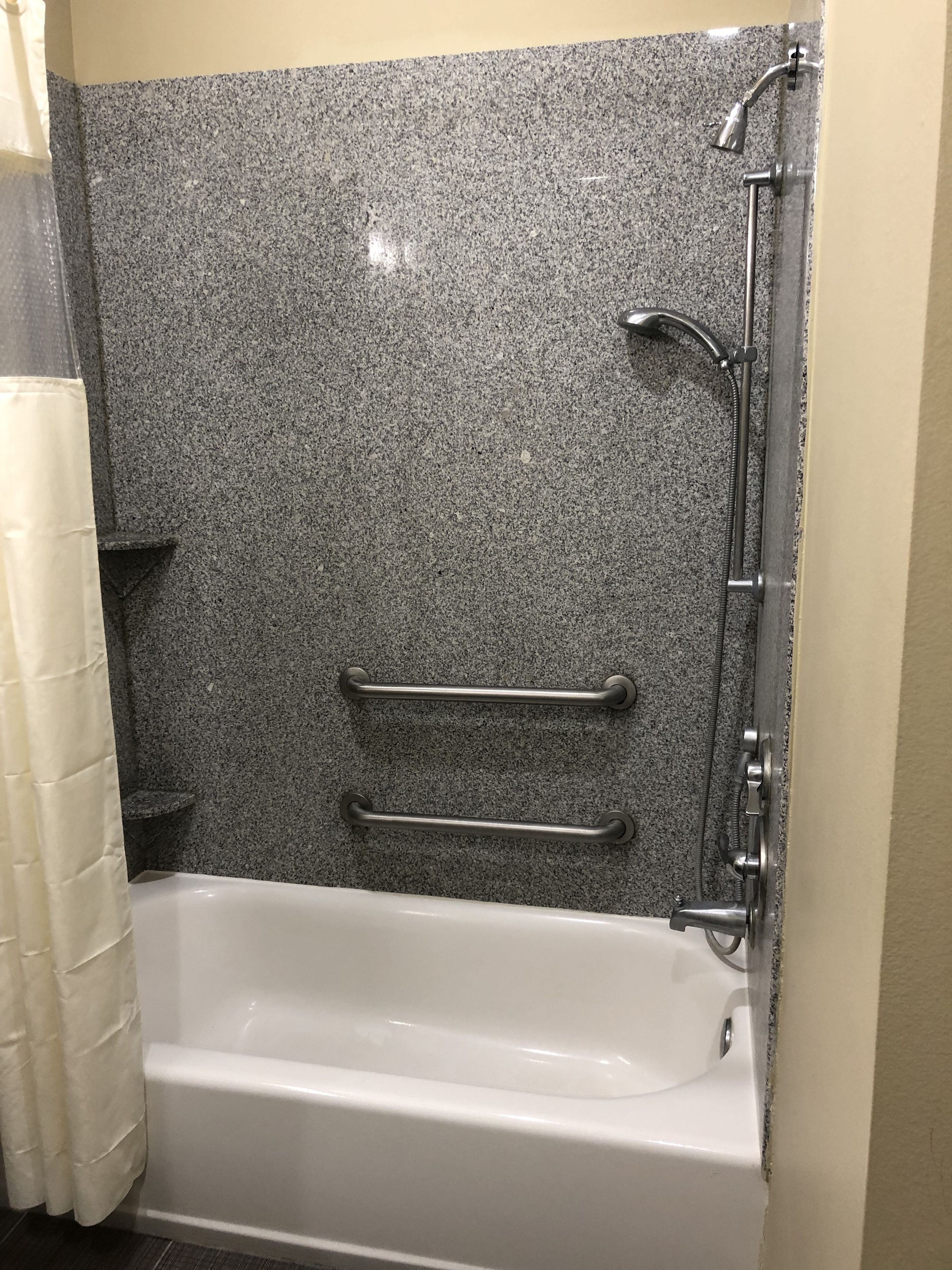 Une salle de bain avec une baignoire blanche, une douche équipée d’un pommeau de douche à main et un porte-serviettes.