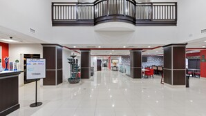 A spacious, modern lobby with a high ceiling, a central staircase, and a reception desk. - Wingate by Wyndham Lake Charles Casino Area (Lake Charles)