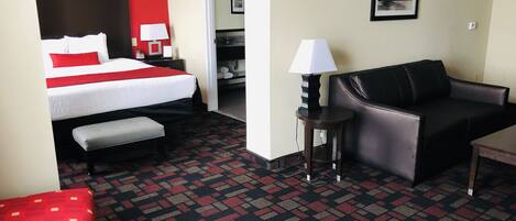 A hotel room with a bed, a sofa, a round table, and a patterned carpet.