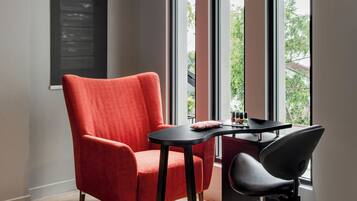 Una habitación moderna con un sillón rojo, una silla negra y una pequeña mesa con un cojín.