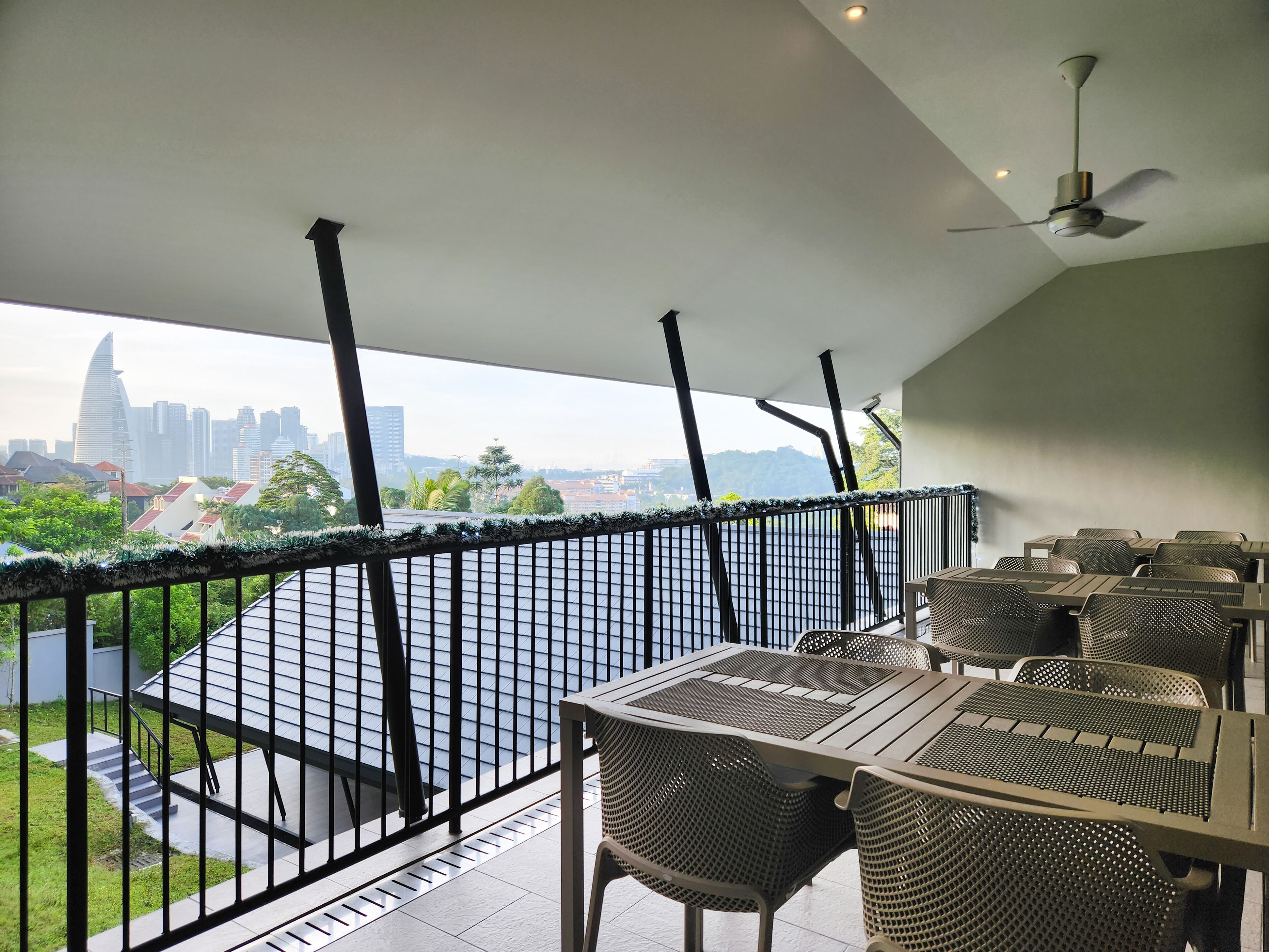 Un balcon avec vue sur les toits de la ville, des sièges d’extérieur et un ventilateur de plafond.