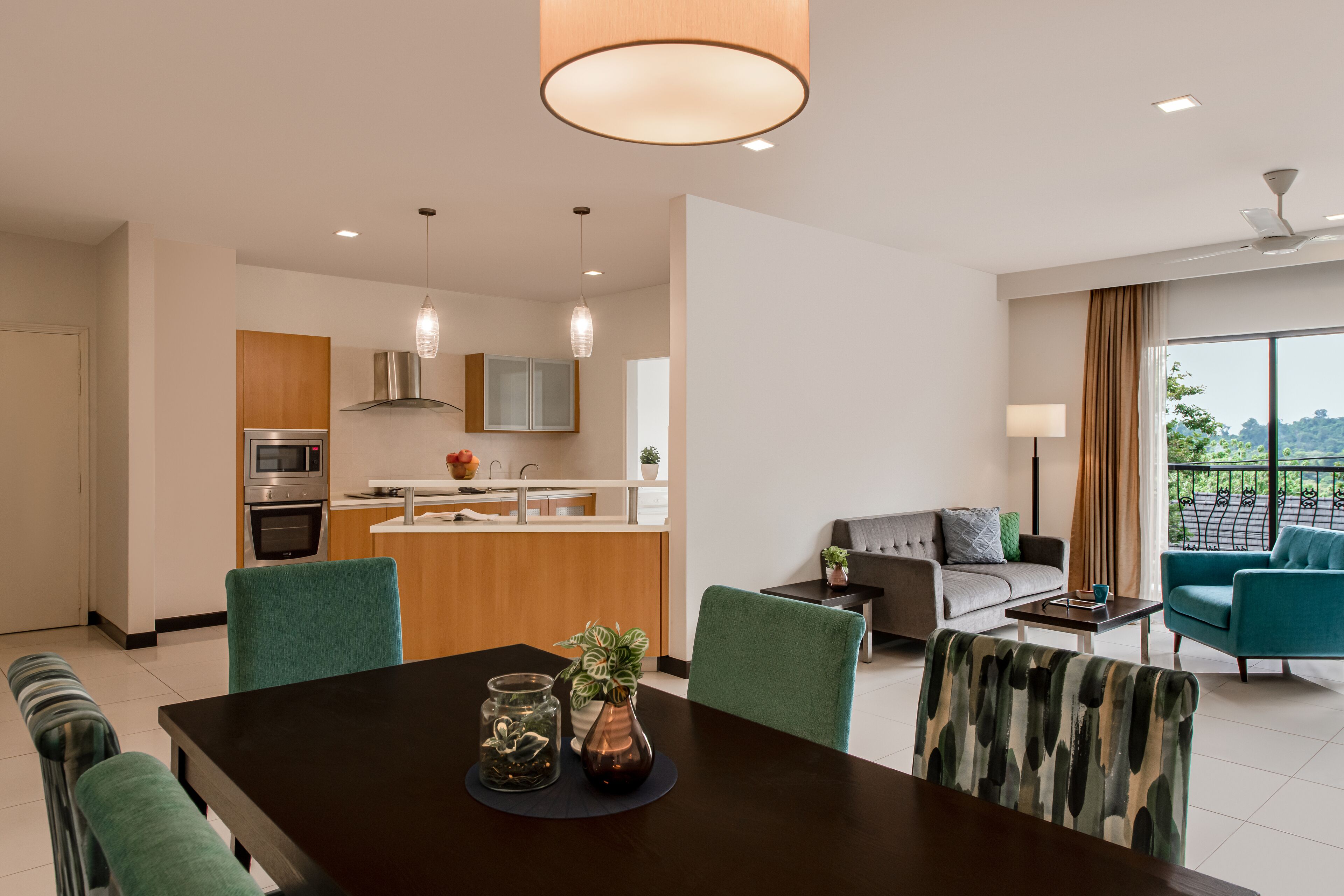 A modern living room with a sofa, a dining table with chairs, and a kitchen area with appliances.