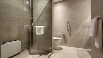 A modern bathroom with a glass shower enclosure, a toilet, and a towel rack.