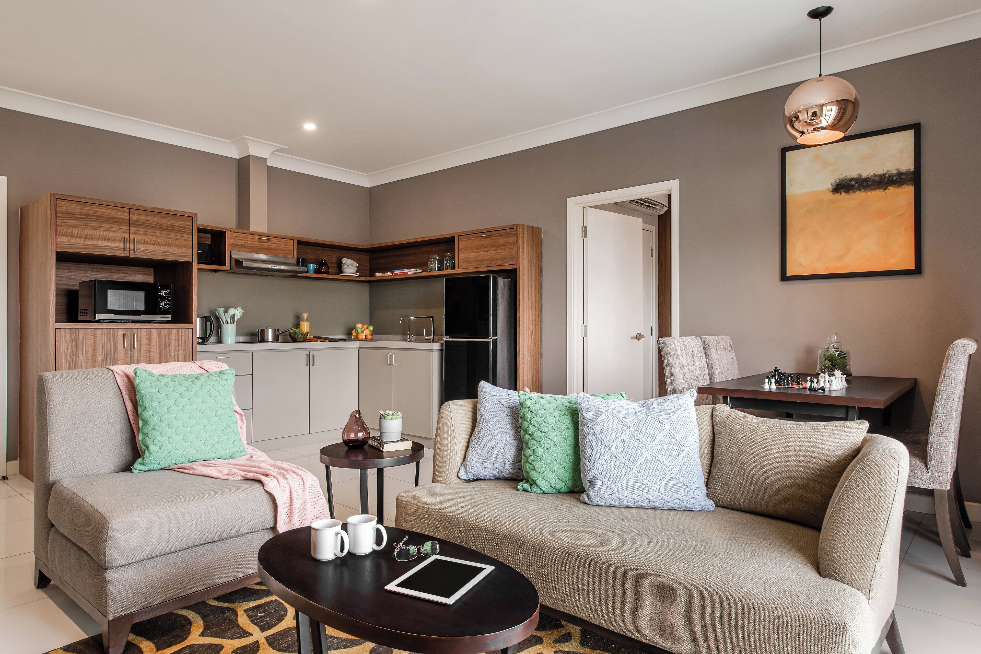 A modern living room with a sofa, coffee table, and a dining area with a table and chairs.