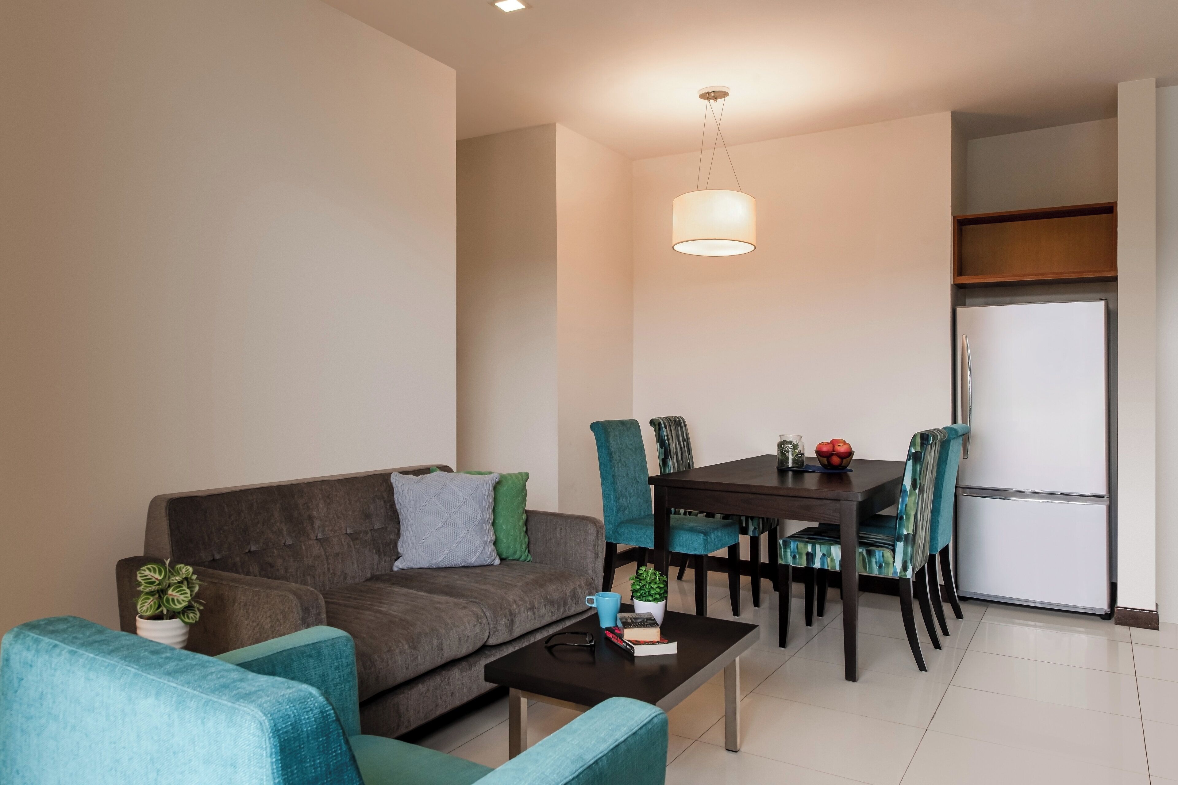 A modern living room with a sofa, a coffee table, and a dining area with chairs and a table.