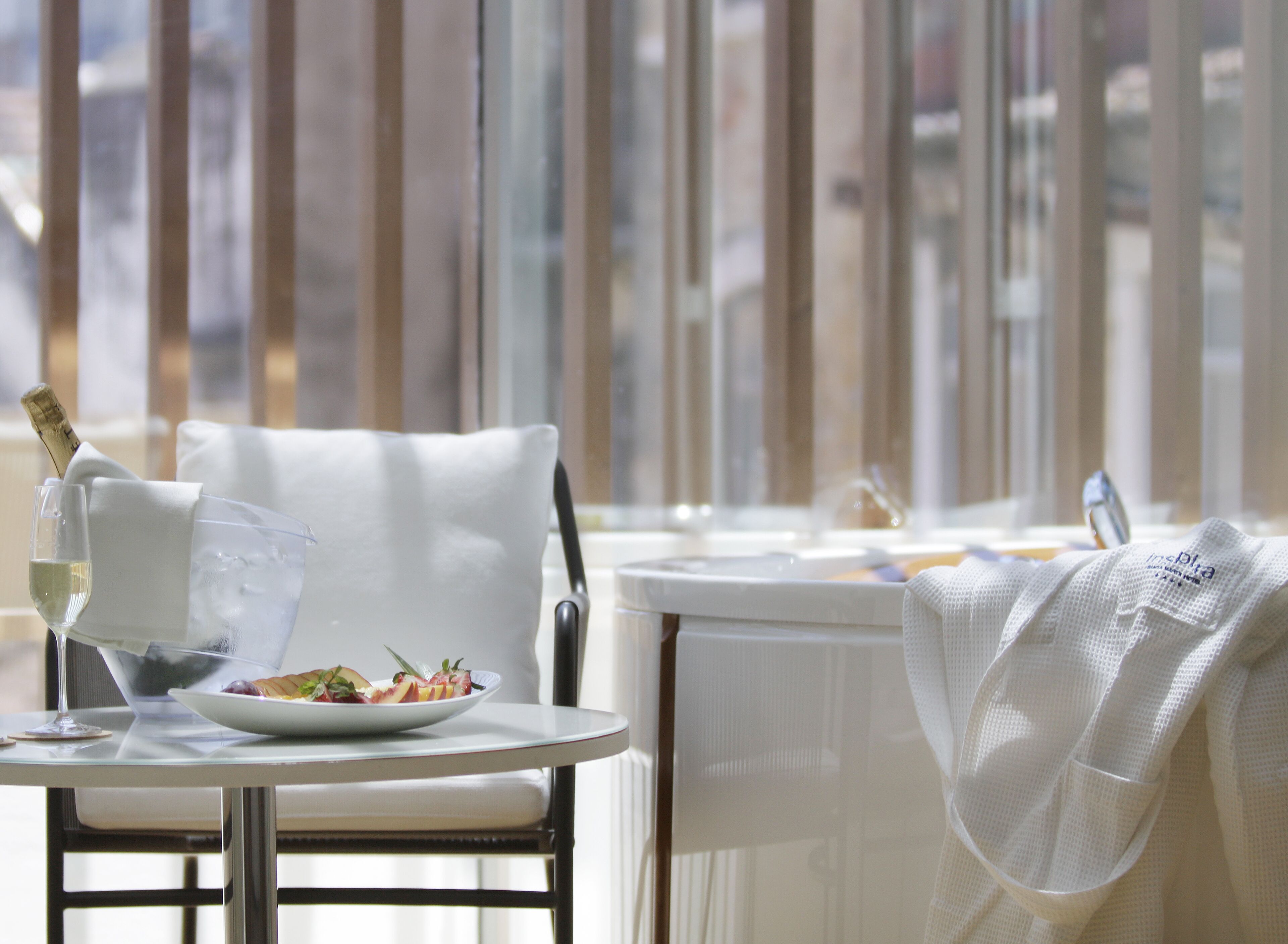 A dining area with a table set for two, a bottle of champagne, and a plate of food.
