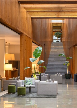 Un vestíbulo moderno con paneles de madera, una escalera y zonas de estar.