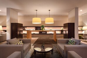 Una sala de estar moderna con dos sofás, una mesa de centro y una cocina al fondo.