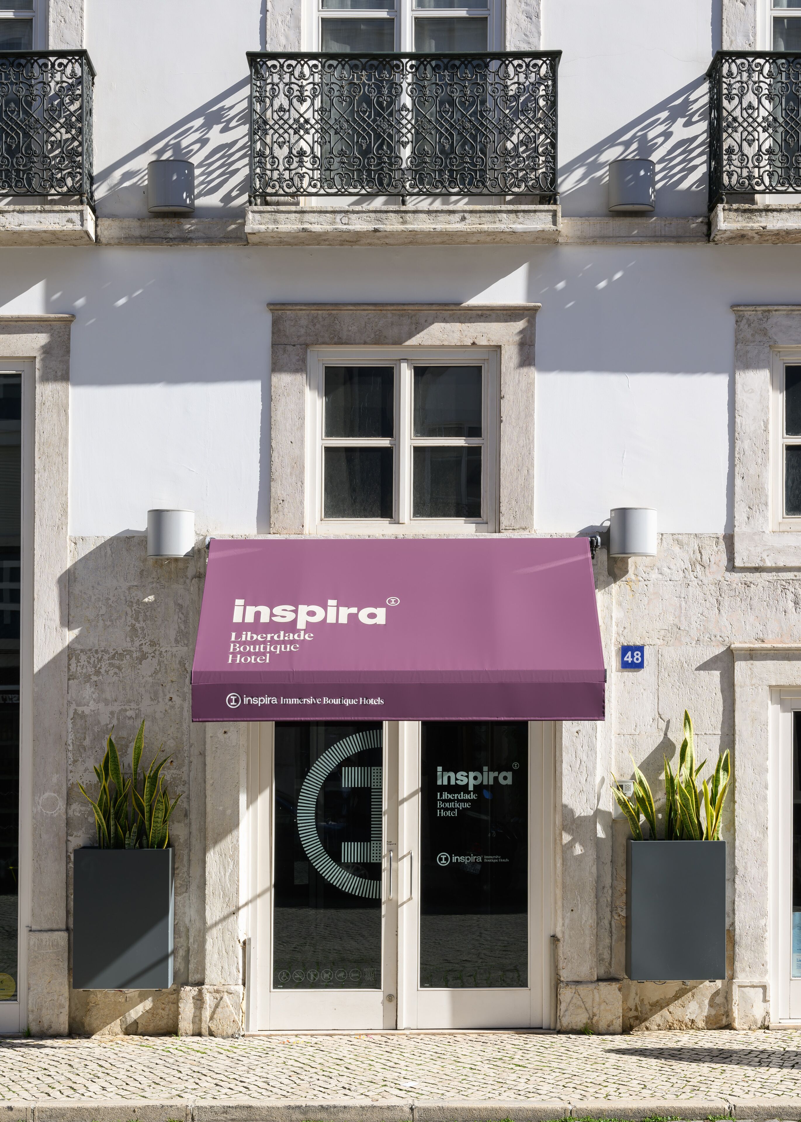 A building with a purple awning labeled "Inspira Boutique Hotel" and a number "48" on the wall.