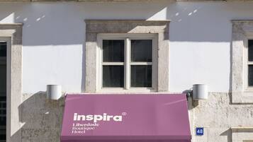 A building with a purple awning labeled "Inspira Boutique Hotel" and a number "48" on the wall.