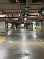 Ένας ευρύχωρος χώρος στάθμευσης με σαφείς πινακίδες που υποδεικνύουν τις εξόδους και ένα καθαρό, καλά συντηρημένο δάπεδο.