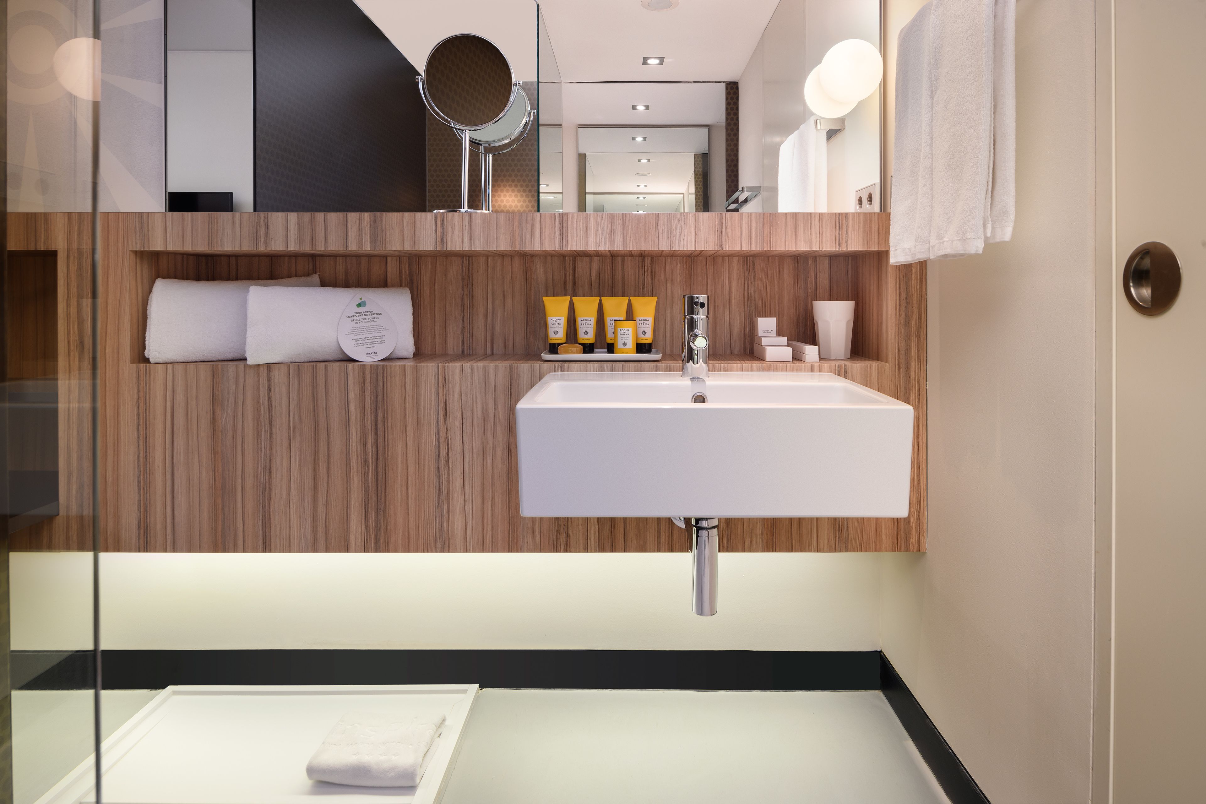 A modern bathroom with a large sink, wooden paneling, a mirror, and toiletries.