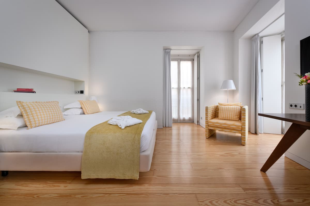 A hotel room with a bed, a chair, a desk, and a TV.