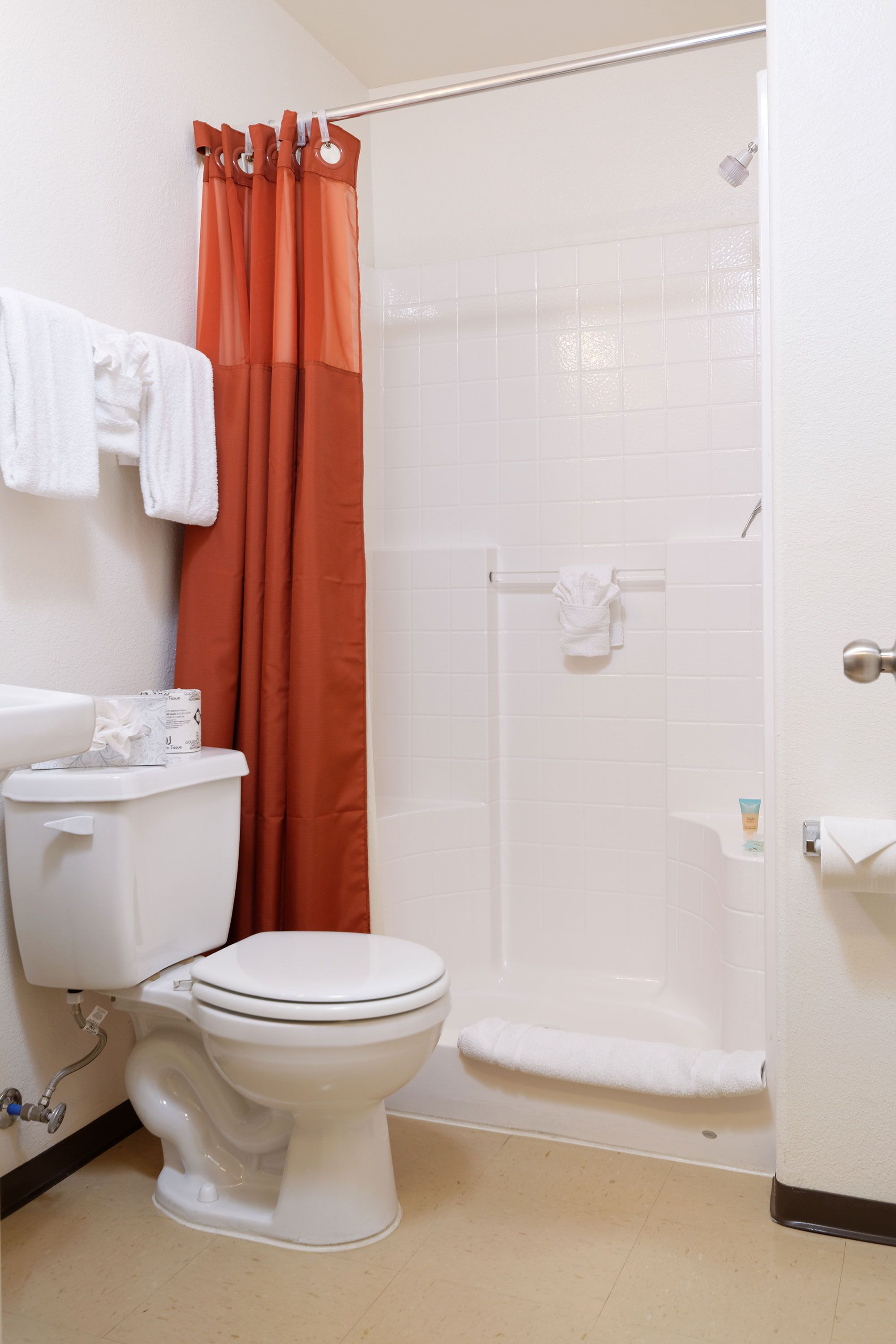 Een badkamer met toilet, douche en een witte badkuip.