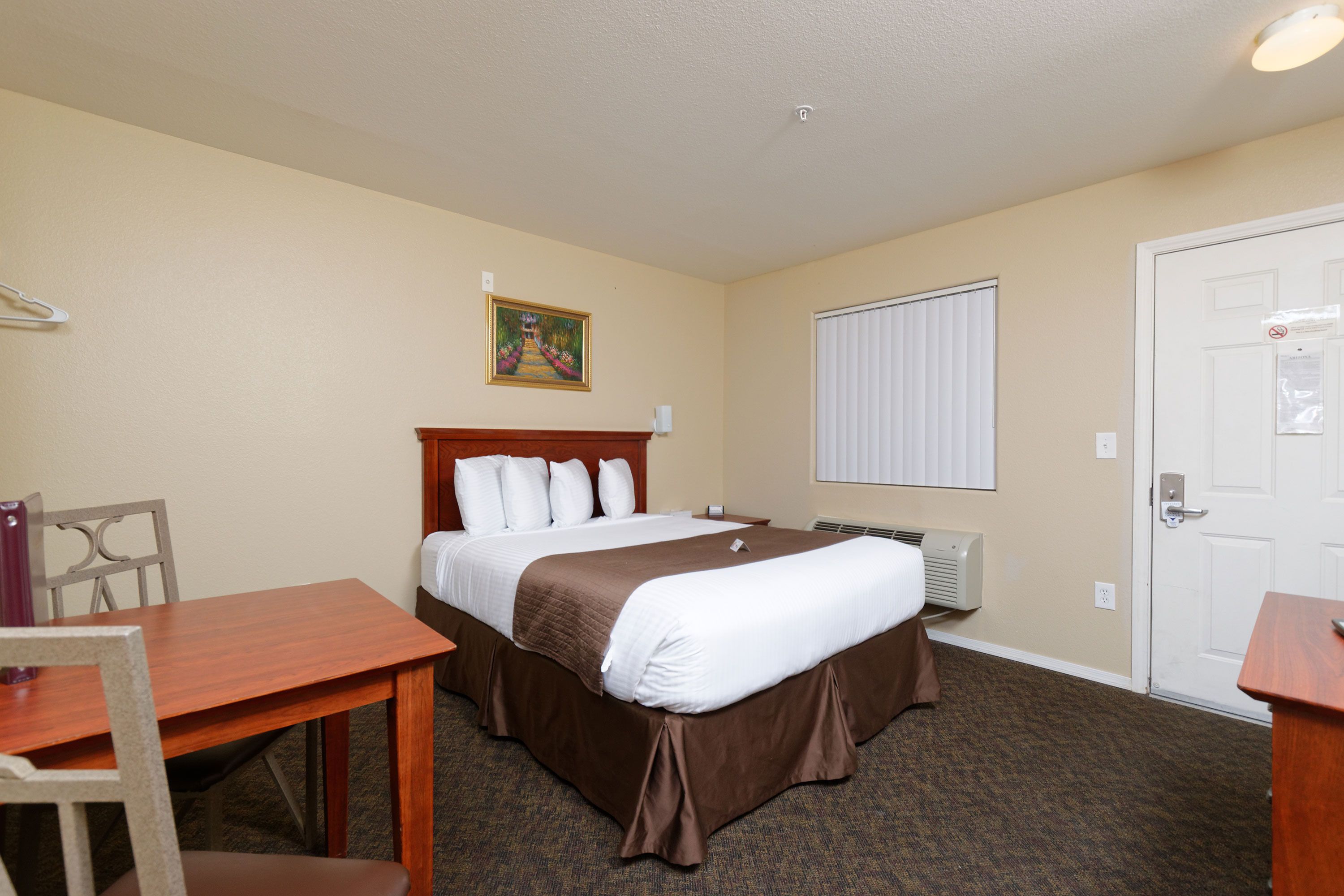 A hotel room with a bed, a desk, and a chair.