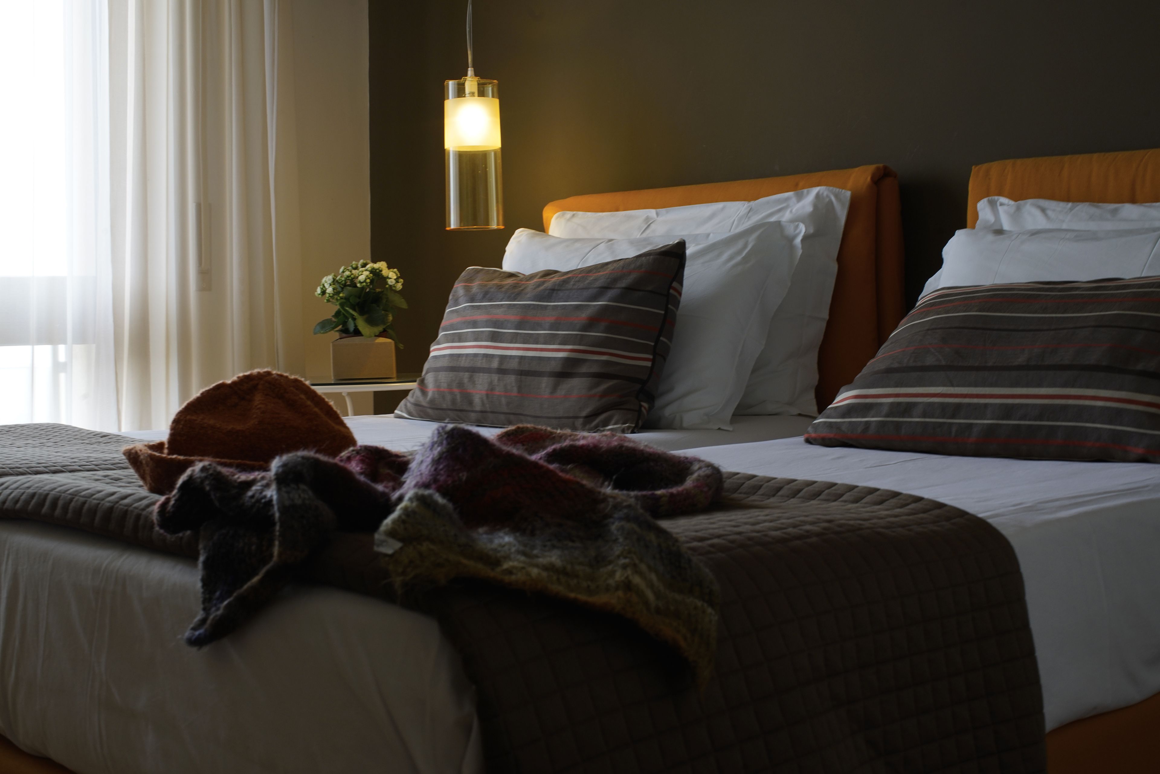 Et hotelværelse med to senge, et natbord med lampe og et vindue med gardiner.