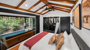A bedroom with a large bed, a ceiling fan, a view of a swimming pool, and a bathroom with a mirror and sink.