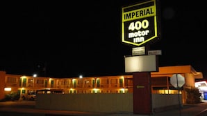 Letrero de motel con la leyenda 'IMPERIAL 400 motor inn' y otro letrero que dice 'limpieza impecable, AMs especiales, tarifas semanales'.